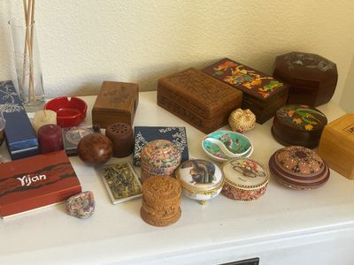 Sale Photo Thumbnail #52: Collection of vintage decorative trinket boxes and small tabletop accents, including carved wooden boxes, painted porcelain containers, and a small Nefertiti motif dish.