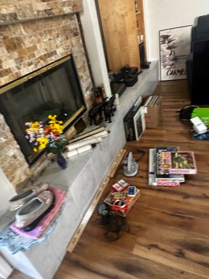 Sale Photo Thumbnail #57: Living room hearth area featuring a stacked stone fireplace, decorative items, board games, shoes, and vinyl records.
