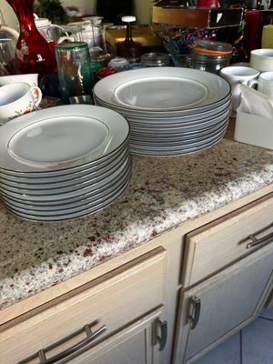 Sale Photo Thumbnail #40: Two stacks of white fine china plates featuring platinum or silver rims, displayed on a kitchen countertop alongside various glassware and mugs.