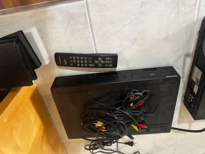 Sale Photo Thumbnail #46: Black Samsung DVD player paired with a Magnavox remote control and tangled AV cables.