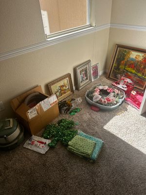 Sale Photo Thumbnail #72: Collection of framed artwork, floral wreaths, seasonal decorations, and household linens resting on a carpeted floor.
