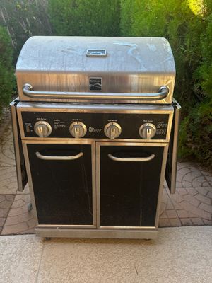 Sale Photo Thumbnail #2: Kenmore 4-burner outdoor gas grill featuring stainless steel hood and lower cabinet doors, showing some outdoor wear.
