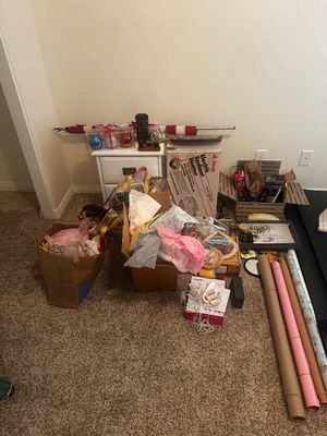 Sale Photo Thumbnail #75: Assortment of household items, gift bags, wrapping paper rolls, electronics in boxes, and a white nightstand.