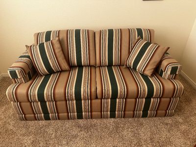 Sale Photo Thumbnail #39: Upholstered two-cushion loveseat featuring a vertical striped pattern in earth tones of green, tan, and brown, complete with two matching throw pillows.