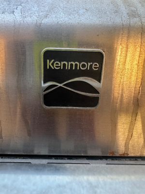Sale Photo Thumbnail #5: Close-up view of a Kenmore brand emblem on a stainless steel appliance surface.
