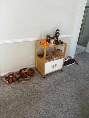 Sale Photo Thumbnail #70: Light wood rolling cart featuring Halloween decor, figurines, and baskets, flanked by additional fall decorations on the floor.