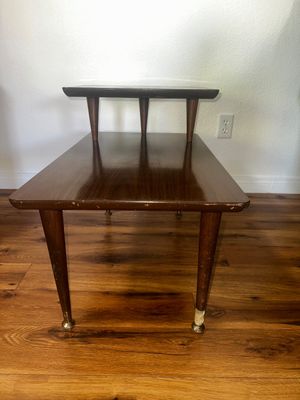Sale Photo Thumbnail #34: Mid-century modern two-tiered wooden side table featuring tapered legs with brass feet, showing light surface wear along the edges.