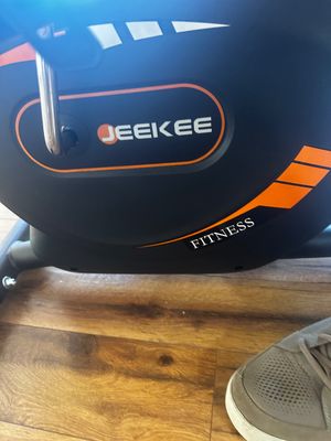 Sale Photo Thumbnail #19: JEEKEE Fitness stationary exercise bike, featuring a black housing with orange accents and a metal pedal arm.