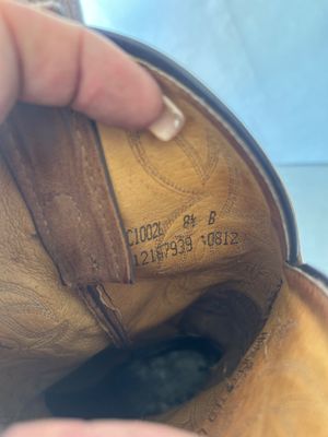 Sale Photo Thumbnail #129: A pair of women's leather Western cowboy boots featuring two-tone brown leather shafts with white cross inlays and decorative embroidery stitching, dark brown leather feet with square toes, and pull straps. Interior stamping indicates style C1002L, size 8