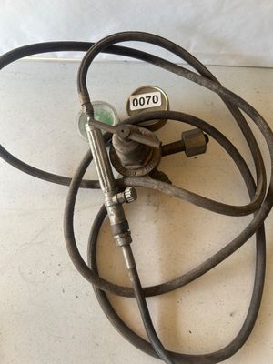 Sale Photo Thumbnail #87: A vintage Victor Equipment Company brass oxygen pressure regulator assembly, featuring dual pressure gauges and T-handle adjustment valve. Includes attached heavy-duty black rubber hosing and a handheld torch attachment with control valve. Shows age-appro