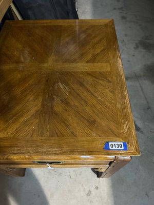 Sale Photo Thumbnail #194: A vintage Thomasville oak end table featuring Asian-inspired design elements, including chow-leg styled base details and a campaign-style brass drawer pull. The table includes a single drawer stamped with the Thomasville logo inside, and a parquetry/patte