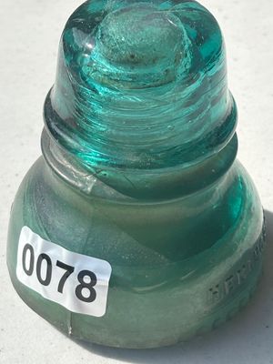 Sale Photo Thumbnail #100: A vintage Hemingray aqua green glass telephone/telegraph insulator. Features threaded interior and embossed maker mark near the base. Shows typical minor wear consistent with age.