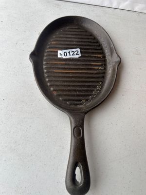 Sale Photo Thumbnail #183: Oval cast iron grill pan with ribbed cooking surface, side pour spouts, and hanging hole in handle. Shows minor surface wear and light rust consistent with age and use.