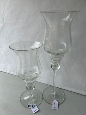 Sale Photo Thumbnail #178: Pair of clear glass pedestal candle holders featuring a flared tulip hurricane top and tiered stem details. Includes two varying heights, suitable for pillar or votive candles.
