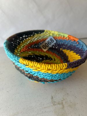 Sale Photo Thumbnail #82: A vibrant, hand-woven small basket bowl featuring a spiraling geometric pattern in shades of turquoise, yellow, orange, purple, brown, and green. Appears to be crafted in a telephone wire or coiled fiber style, typical of South African tribal handcrafts. 
