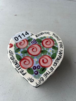 Sale Photo Thumbnail #175: A heart-shaped ceramic trinket box featuring hand-painted floral designs, black and white checkered border details, and inspirational lettering. The inside reads 'CHERISH YOUR FRIENDS', while the lid reads 'THE MOST ESSENTIAL THING FOR HAPPINESS IS THE GI