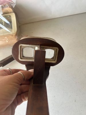 Sale Photo Thumbnail #159: An antique hand-held stereoscope viewer featuring an embossed metal hood with ornate floral and crest details stamped 'MONARCH', a wooden body, folding handle, glass lenses, and slide track. Accompanied by a stack of vintage stereoview/stereograph cards s