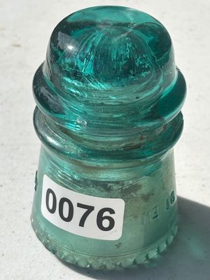 Sale Photo Thumbnail #98: Vintage teal/aqua colored heavy glass telegraph or telephone line insulator featuring a sharp petticoat bottom rim and molded markings (No. 16 visible). Shows age-appropriate wear and minor internal stress marks/bubbles.