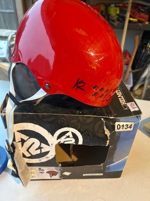 Sale Photo Thumbnail #198: A red K2 Phase Pro ski or snowboard helmet featuring ventilation slots, ear pads, and chin strap. Comes with its original K2 retail packaging box showing model Phase Pro.