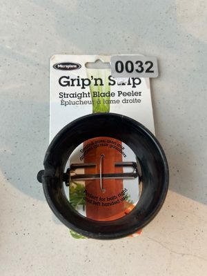 Sale Photo Thumbnail #32: A Microplane Grip'n Strip straight blade vegetable peeler in original packaging. Designed for both right and left-handed use, featuring a black circular grip and stainless steel blade.