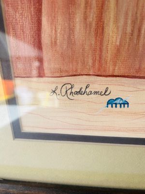 Sale Photo Thumbnail #144: Original framed colored pencil or pastel drawing depicting a Southwestern adobe pueblo structure with a bird flying in the sky, signed in the lower corner 'L. Rhodehamel'. Double matted and presented in a dark rustic wood frame. Measures approximately 32 