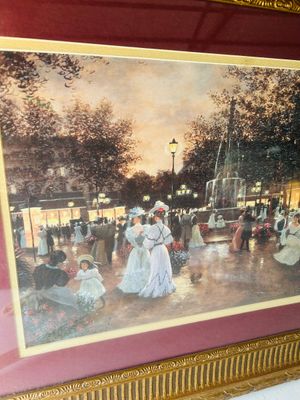 Sale Photo Thumbnail #142: Framed art print depicting an elegant Victorian-era street scene with figures strolling near a fountain, surrounded by trees and illuminated streetlights. Features double matting with a burgundy outer mat and a inner gold trim accent. Housed in an ornate 