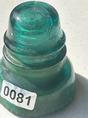 Sale Photo Thumbnail #103: A vintage emerald green glass glass insulator featuring threaded interior and heavy glass construction. Displays typical mold lines and air bubbles from manufacturing. Good condition overall with minimal surface wear.