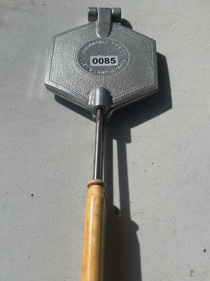 Sale Photo Thumbnail #107: A vintage handheld hexagonal cast aluminum pizzelle or waffle iron by Vitantonio Mfg. Co., Cleveland 6, Ohio. Features long metal rods with turned wooden handles.