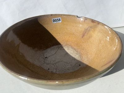 Sale Photo Thumbnail #59: Large wheel-thrown studio art pottery bowl featuring a ribbed exterior with dark olive green glaze and a warm tan-gold glazed interior. Signed 'Pask 83' (or similar artist signature) on the unglazed foot ring base. Dated 1983. Shows a small chip along the