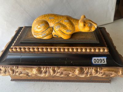 Sale Photo Thumbnail #132: An Art Deco style decorative trinket or keepsake box featuring a reclining yellow crackle-glaze ceramic leopard finial on a lid. The box is constructed of wood with dark finish trim and ornate gilt beaded and carved scroll accents. The lid lifts off to re