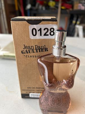 Sale Photo Thumbnail #190: Jean Paul Gaultier "Classique" Eau de Parfum natural spray in signature torso-shaped glass bottle with lace design motif. Includes original cardboard packaging box. Bottle appears to be mostly full.
