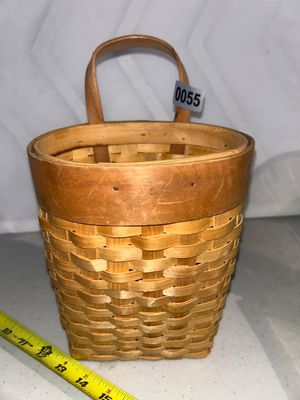 Sale Photo Thumbnail #55: A woven wood splint basket with a single arch handle designed for hanging. Features a reinforced wooden band rim and flat back/base. Measures approximately 8-9 inches tall (excluding handle). Good condition with minor signs of handling.