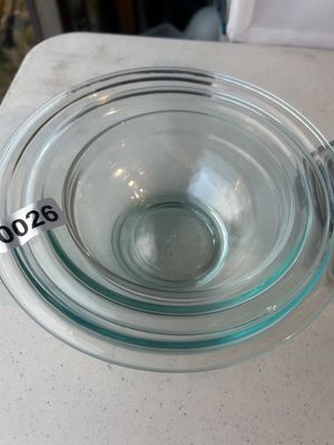 Sale Photo Thumbnail #26: A set of clear, nested glass mixing bowls with a slight greenish tint. Ideal for prep work, mixing, and kitchen storage. Appears in good overall condition with no visible major cracks or chips.