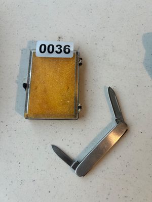 Sale Photo Thumbnail #36: Compact stainless metal pocket knife featuring two folding blades, accompanied by a small clear plastic display or storage box with foam interior insert. Blade marked with manufacturer details. Good pre-owned condition.