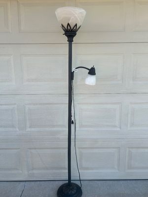 Sale Photo Thumbnail #67: Black metal torchiere floor lamp featuring an upper main light with a marbled white frosted glass shade, decorative crown motif detail, and an attached adjustable gooseneck reading light with a matching shade. Round decorative heavy base with floral scrol