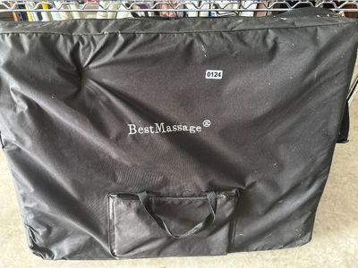 Sale Photo Thumbnail #186: A BestMassage portable folding massage table featuring black vinyl upholstery and a heavy-duty black fabric carrying bag with handles and an accessory pocket. Appears lightly used.