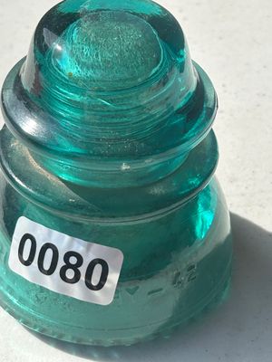 Sale Photo Thumbnail #102: A vintage aqua blue-green heavy glass insulator, marked with '42' on the lower skirt. Features a threaded dome center and petticoat skirt design. Appears in good vintage condition with minor surface wear consistent with age and use.