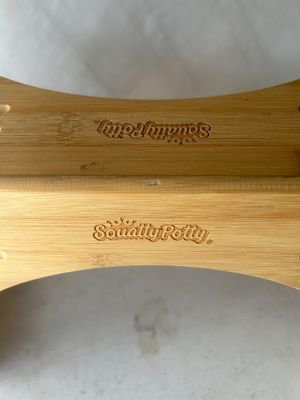 Sale Photo Thumbnail #131: A Squatty Potty bathroom stool constructed from natural bamboo. Features grooved footrests and engraved brand logos. Designed to fit around the base of a standard toilet to improve posture. In good used condition with light surface wear.