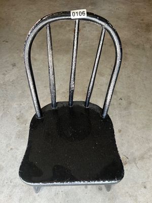 Sale Photo Thumbnail #161: A vintage black painted wooden chair with a spindle back design, likely sized for a child or doll display. The chair shows distress and wear to the black paint, revealing the light wood underneath, adding vintage character. Solid wood construction.