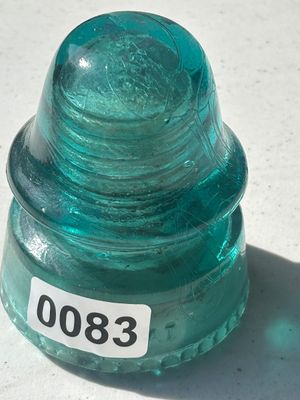 Sale Photo Thumbnail #105: A vintage heavy aqua green/blue glass insulator featuring a threaded inner core and corrugated rim along the bottom base. Shows light wear and mold marks typical of vintage glass line insulators.