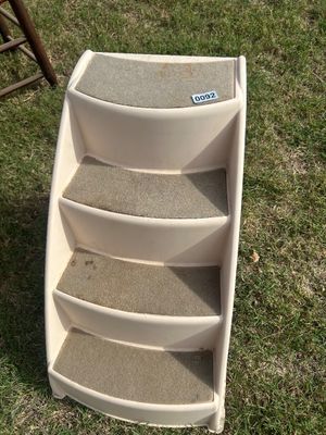 Sale Photo Thumbnail #126: A cream-colored molded plastic 4-step pet staircase featuring gray carpeted treads to provide traction for dogs or cats. Designed to assist pets in reaching beds, couches, or vehicles. Shows light wear and slight discoloration from normal use.