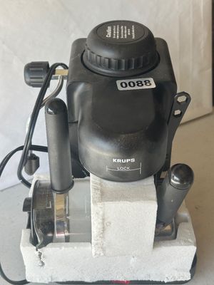 Sale Photo Thumbnail #114: Krups black countertop espresso/cappuccino maker, complete with glass carafe, filter holder, and steam wand. Features a steam cap safety lock. Item comes partially packed in original Styrofoam packaging. Lot tag 0088 attached.