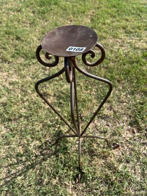 Sale Photo Thumbnail #164: Decorative metal/wrought iron stand with scrollwork accents, featuring a flat top platform designed to hold a pillar candle or small potted plant. Shows light outdoor patina and surface wear.