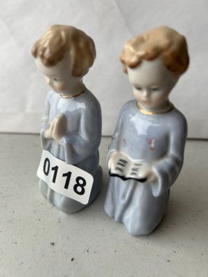 Sale Photo Thumbnail #179: A pair of small porcelain figurines featuring kneeling boys in light blue robes with gold accents, one praying and one holding an open book or songbook. Features delicate hand-painted facial details. In good condition with no visible cracks or major chips
