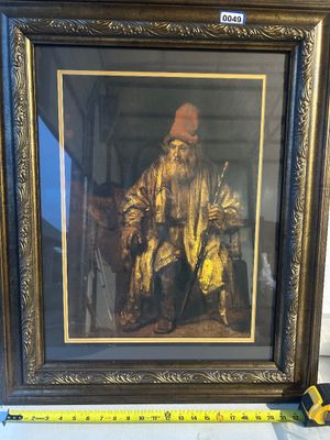 Sale Photo Thumbnail #49: Framed print featuring an elderly bearded man in a red hat and gold-toned cloak holding a staff, in the style of Rembrandt van Rijn. Encased in a gold and dark ornate composite frame with double matting. Measures approximately 22 inches wide at the base.