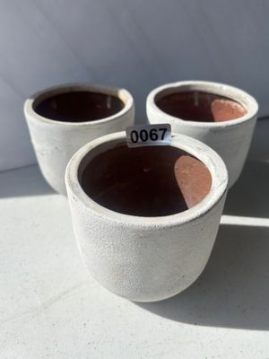 Sale Photo Thumbnail #81: A set of three matching small planter pots featuring a white textured exterior finish over terra cotta ceramic, ideal for succulents or small houseplants.