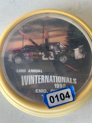 Sale Photo Thumbnail #153: Round plastic novelty wall clock featuring stock car racing graphic for the '33rd Annual Winternationals 1998 Enid, OK'. Shows some surface wear and light scratching on the clear plastic lens.