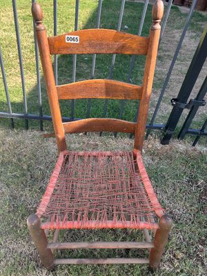 Sale Photo Thumbnail #79: A vintage rustic ladder-back dining or accent chair featuring turn-of-the-century styling with finial post tops, curved back slats, and a hand-woven orange/red string/cord seat. Shows age-appropriate wear and patina on the wood frame.