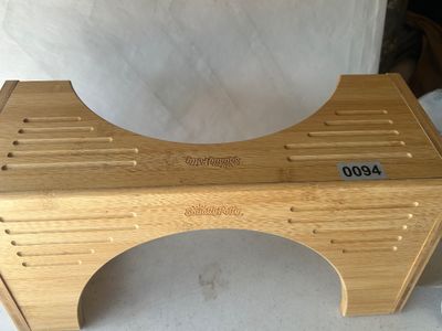 Sale Photo Thumbnail #130: A Squatty Potty bathroom stool constructed from natural bamboo. Features grooved footrests and engraved brand logos. Designed to fit around the base of a standard toilet to improve posture. In good used condition with light surface wear.