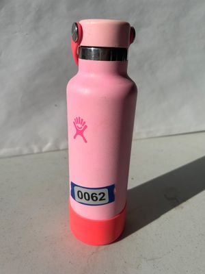 Sale Photo Thumbnail #71: A pink vacuum-insulated stainless steel Hydro Flask water bottle featuring a matching pink screw-top lid with a carrying loop and a dark pink silicone bottom boot. Appears in good pre-owned condition.